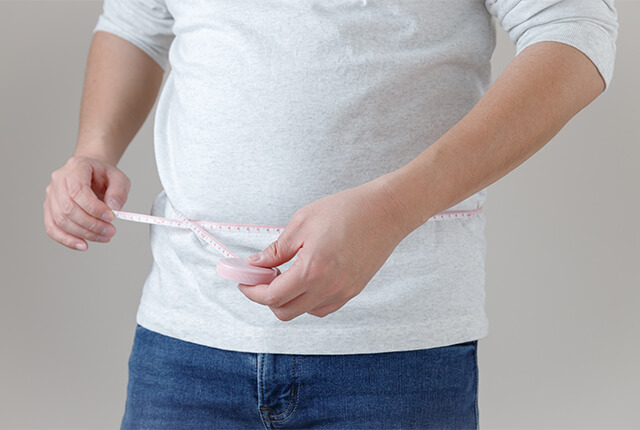 メジャーで腹囲を測っている男性